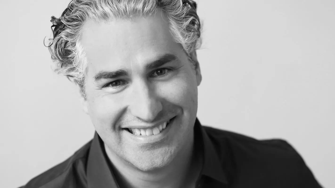 man smiling at the camera in black shirt in black and white